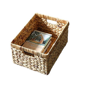 Rectangular woven wicker basket with handles, containing a book, ideal for storage and organization.